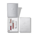 Un set de regalo de belleza plateado y abierto que muestra productos para labios: un delineador, labiales en barra, un labial velvet doble y un gloss, junto a su caja a juego, con una presentación elegante y minimalista.