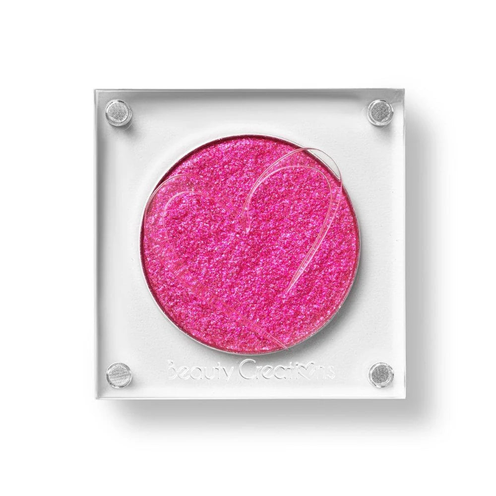 Un estuche cuadrado de sombra de ojos de Beauty Creations en acrílico transparente con un hueco redondo de sombra rosa intenso brillante, con un recorte en forma de corazón en la tapa.