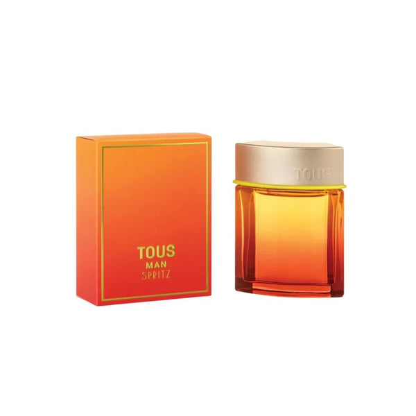 Botella de perfume "Tous Man Spritz" con degradado de naranja cálido a amarillo vibrante y tapón plateado con el logo de la marca, junto a su caja a juego con un fino borde verde neón y tipografía en amarillo y verde neón.