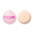 Dos esponjas redondas de polvo para maquillaje sobre un fondo blanco: una esponja rosa de Beauty Creations con una correa en forma de corazón junto a una esponja melocotón lisa y de aspecto suave.